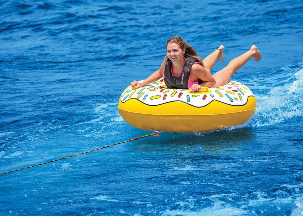 Young woman riding in a yellow pull-behind float tube designed to look like a donut with colored sprinkles.