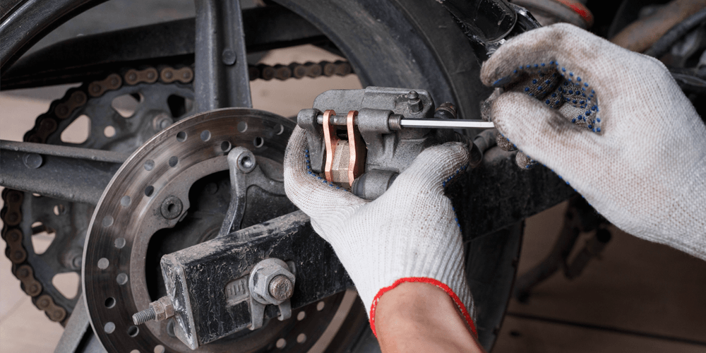 Person changing brake pads on a motorcycle