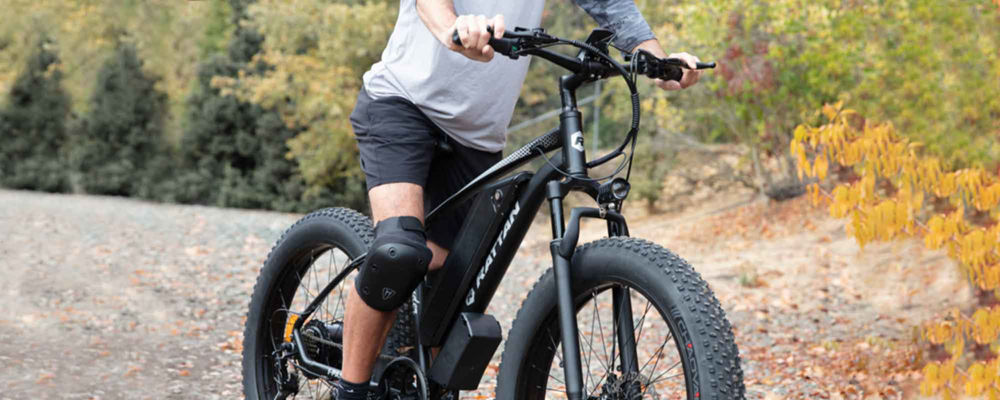 Male riding an ebike on an unpaved trail through the woods