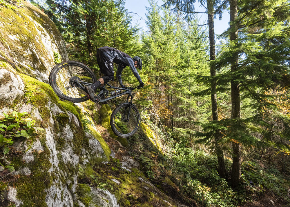 Man riding a mountain bike down a rocky slope in the forest