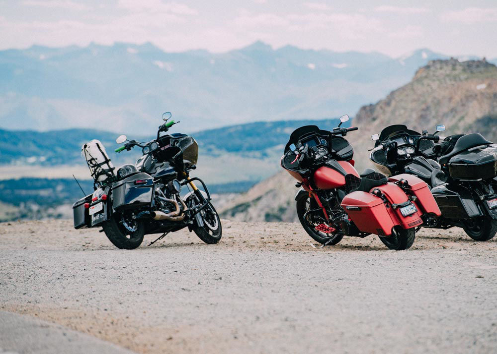 parked motorcycles on the side of a highway with mountains in the background