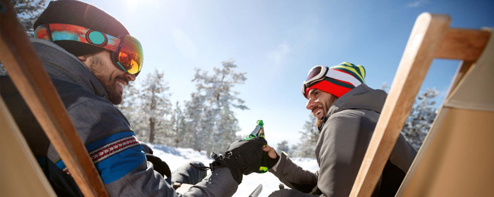 Two male friends having beer after a snowmobile ride