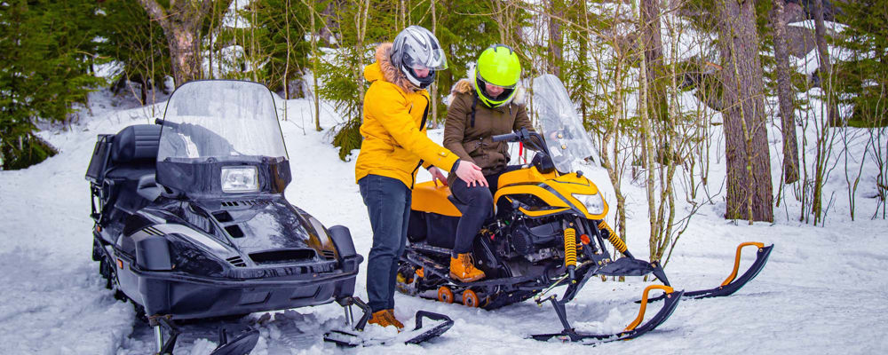 Snowmobile instructor giving a student tips on riding their snowmobile