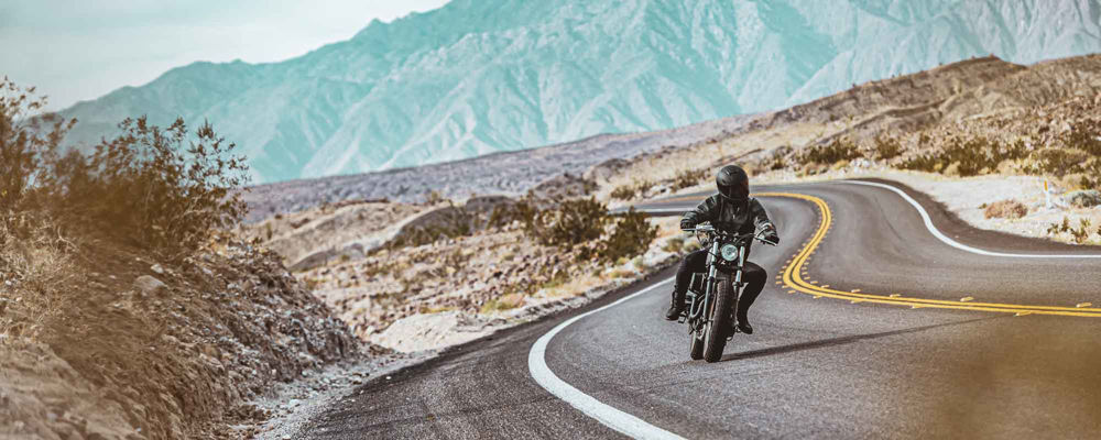 Person riding their motorcycle on a winding road in the desert