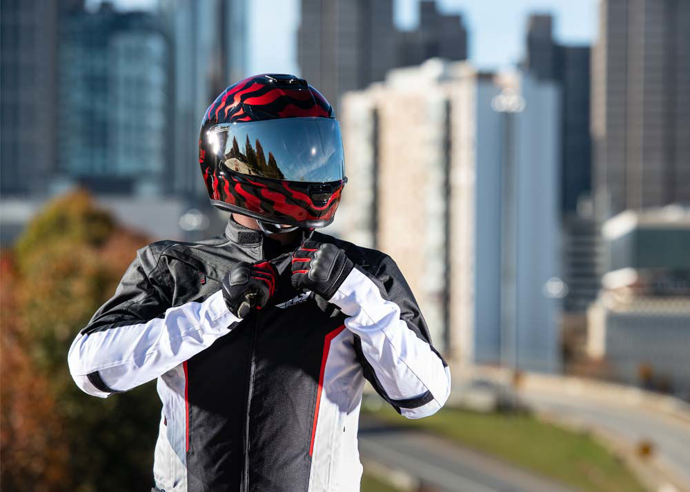Person getting ready for a motorcycle ride, zipping up their jacket. City skyline in background