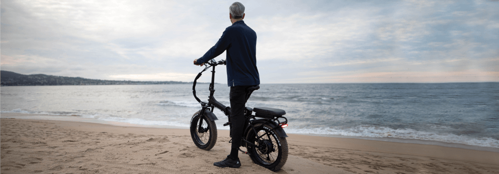 Man standing on a beach with his Rattan eBike
